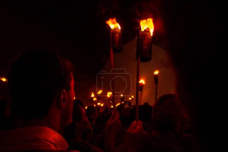 Photo for Fogareu Procession. A believer's back and several other people dressed in tunics and holding a fire torch in a religious procession in Goias. - Royalty Free Image