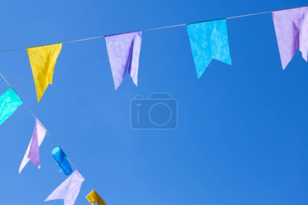 Deux cordes avec des drapeaux colorés suspendus avec ciel bleu en arrière-plan. Avec espace pour le texte.