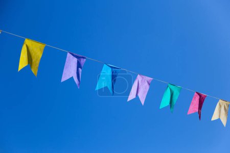 Une corde avec plusieurs drapeaux colorés suspendus avec ciel bleu en arrière-plan. Avec de l'espace pour écrire.