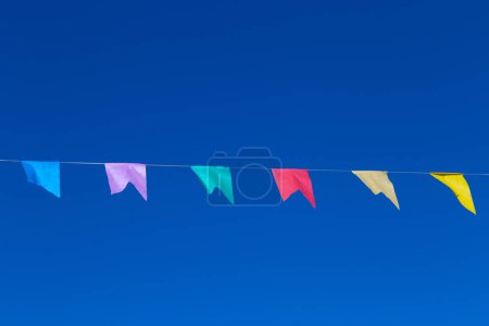 Une corde avec plusieurs drapeaux colorés suspendus avec ciel bleu en arrière-plan. Avec de l'espace pour écrire.