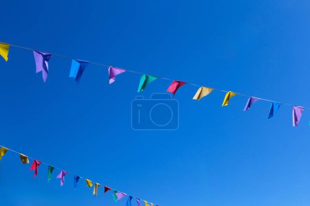  Deux cordes avec des drapeaux colorés suspendus avec ciel bleu en arrière-plan. Avec espace pour le texte.