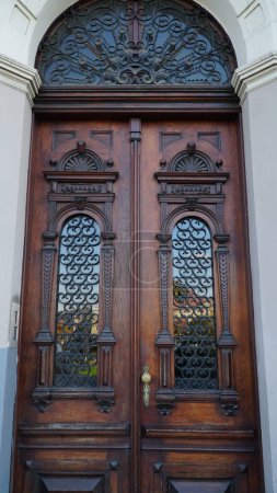 Foto de Puerta. Viejas puertas de entrada de madera con mango de latón en la ciudad. Puerta arqueada. Una hermosa puerta de calle con un arco. - Imagen libre de derechos