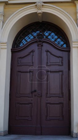 Foto de Puerta. Viejas puertas de entrada de madera con mango de latón en la ciudad. Puerta arqueada. Una hermosa puerta de calle con un arco. - Imagen libre de derechos