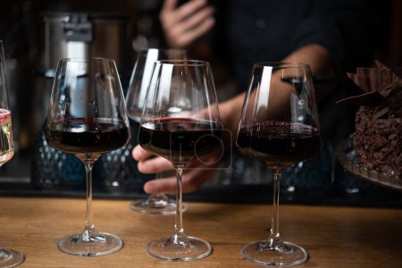 Téléchargez les photos : Homme prenant un verre avec du vin rouge de la table de bar servi - en image libre de droit