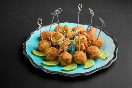 Téléchargez les photos : Cocktails de fruits de mer dans des tasses et des gâteaux de poisson avec des bâtonnets de bois et des tranches de citron vert sur un plateau de plue - en image libre de droit