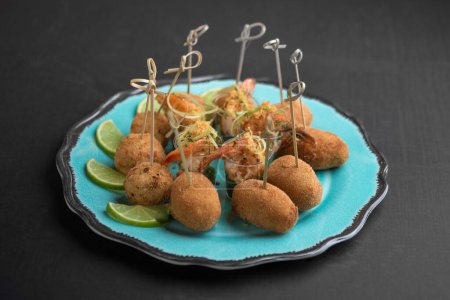 Photo for Seafood cocktails in cups and fish cakes with wooden sticks and lime slices on plue platter - Royalty Free Image