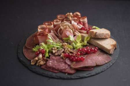 Photo for Closeup of cured meat on black stone platter - Royalty Free Image
