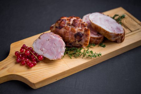 Foto de Rollo de cerdo al horno servido con tomillo y grosellas rojas - Imagen libre de derechos