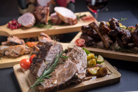 Téléchargez les photos : Délicieuse viande cuite au four et rôtie avec des herbes servies sur une table festive avec du vin - en image libre de droit