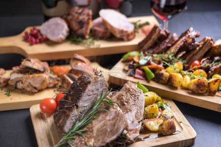 Téléchargez les photos : Délicieuse viande cuite au four et rôtie avec des herbes servies sur une table festive avec du vin - en image libre de droit