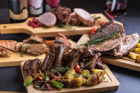 Photo for Holiday table with variety of baked and roast meat served with wine - Royalty Free Image
