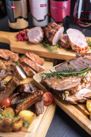 Photo for Holiday table with variety of baked and roast meat served with wine - Royalty Free Image