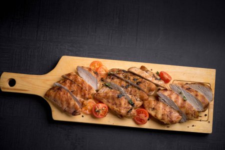 Photo for Grilled chicken fillet with thyme and cherry tomatoes on wooden board - Royalty Free Image