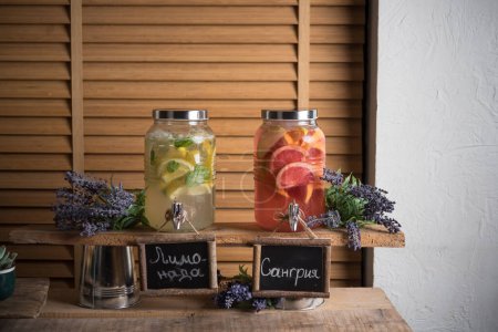 Foto de Bebidas de limonada y sangría servidas en elegantes frascos de vidrio con tapones - Imagen libre de derechos