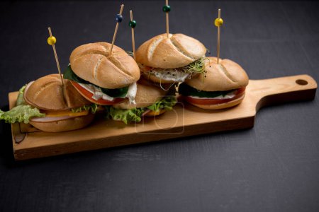 Téléchargez les photos : Délicieux hamburgers percés de bâtons en bois servis sur une planche en bois - en image libre de droit