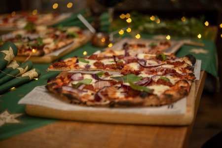 Foto de Primer plano de pizza en rodajas servida en mesa festiva con guirnalda - Imagen libre de derechos