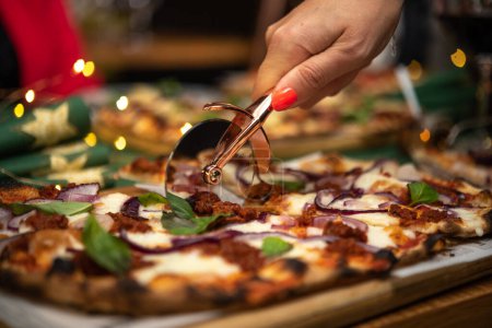 Téléchargez les photos : Gros plan de femme coupant pizza avec coupe-pizza - en image libre de droit