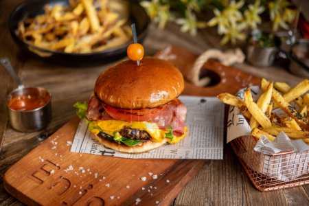 Téléchargez les photos : Cheeseburger avec bacon et frites avec des fleurs de printemps floues sur le fond - en image libre de droit