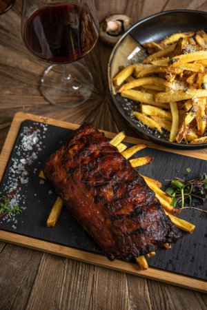 Photo for Delicious dinner with smoked pork ribs, french fries and red wine - Royalty Free Image