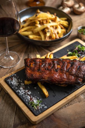 Photo for Smoked pork ribs served with french fries and red wine - Royalty Free Image