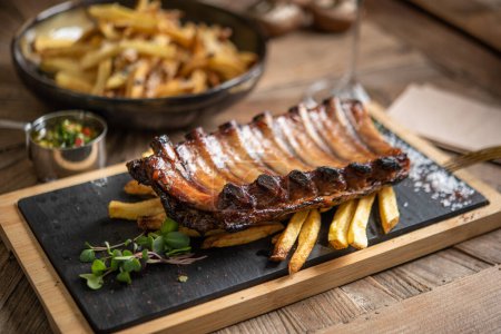 Photo for Smoked pork ribs served with french fries - Royalty Free Image
