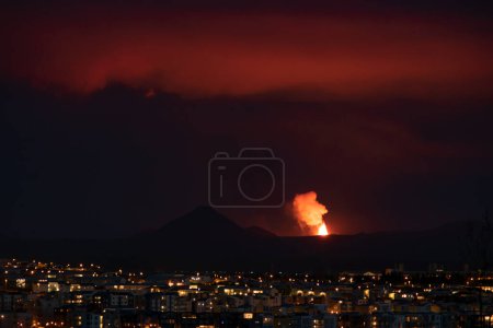Foto de Volcán en erupción sobre casas vecinales Reykjavik - Imagen libre de derechos