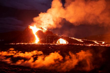 Foto de Volcano cone flowing lava down flanks, night landscape - Imagen libre de derechos