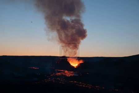 Foto de Pequeño avión sobre el volcán en erupción al amanecerPequeño avión volando sobre el volcán al amanecer Islandia - Imagen libre de derechos