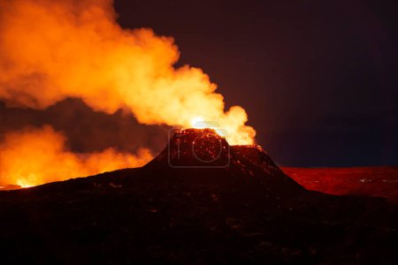 Foto de Erupción nocturna cerca del humo del cono volcánico Islandia - Imagen libre de derechos