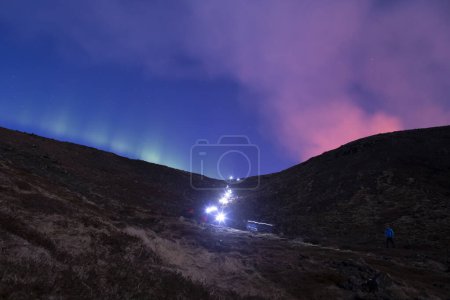Foto de Hiker headlamps long exposure volcano smoke and aurora borealis - Imagen libre de derechos