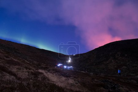 Foto de Hiker headlamps long exposure volcano smoke and aurora borealis - Imagen libre de derechos