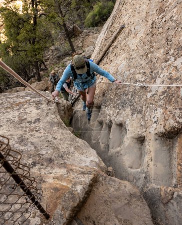 Frau klettert im Mesa Verde Nationalpark Steinstufen hinauf, die aus Felsen gehauen wurden