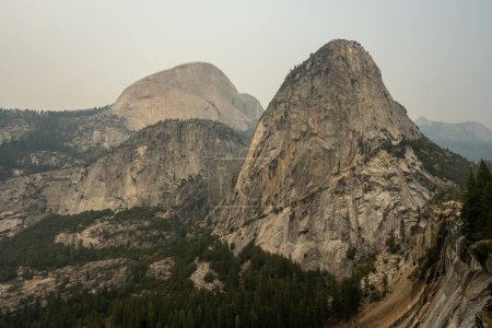 Foto de Liberty Cap con Mount Broderick y Half Dome en la distancia en el día ahumado en Yosemite - Imagen libre de derechos