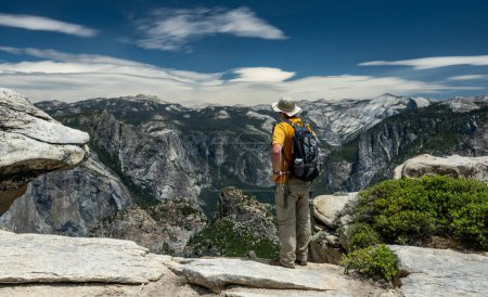Foto de Caminante con camisa amarilla hace una pausa para mirar por encima de la grandeza del Parque Nacional Yosemite - Imagen libre de derechos