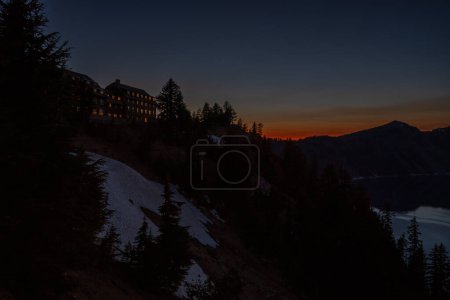 Photo for Crater Lake Lodge Stands High Above Snow Fields and Crater Lake Below at Dusk - Royalty Free Image