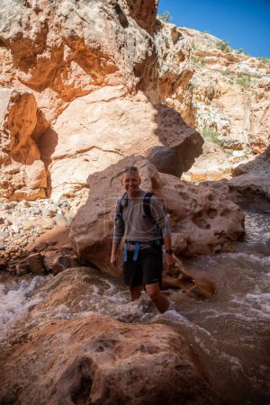 Man With Backpack Stands Knee Deep In Rushing Sulphur Creek in Capitol Reef