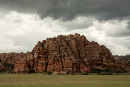 Storm Clouds Over Red Rock Formation with Green Field in Zion