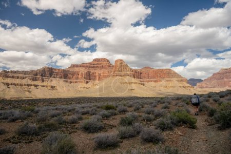 Woman Hikes Across Flat Section of the Tonto Trail with Formations and Clouds Abundant