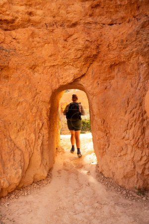 Mujer camina fuera del túnel a través de Hoodoo en Bryce Canyon