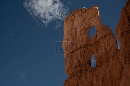 Dos agujeros se forman en Hoodoo estrecho para mostrar el cielo azul en Bryce Canyon