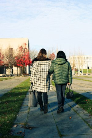 Foto de Dos mujeres caminando por una calle con abrigos en la ciudad - Imagen libre de derechos