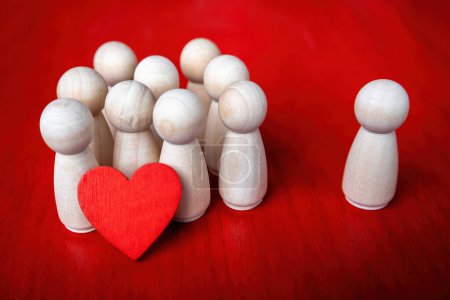 Téléchargez les photos : Groupe de figurines en bois tenant un cœur rouge et une figure se tient par lui-même - en image libre de droit