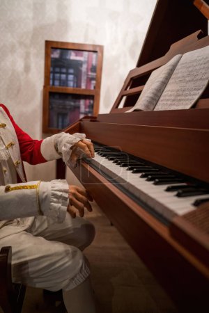 Téléchargez les photos : Mains d'un homme portant un costume de rocco traditionnel du XVIIe siècle avec piano. - en image libre de droit