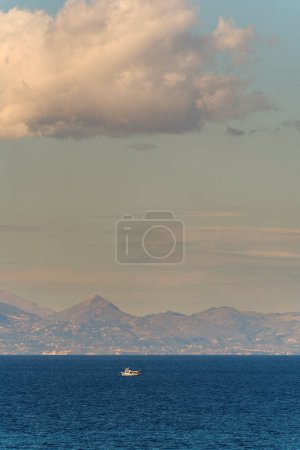 Ein Boot segelt im blauen Mittelmeer und in den Bergen an einem Ort namens Drosia auf der Insel Zakynthos, Griechenland