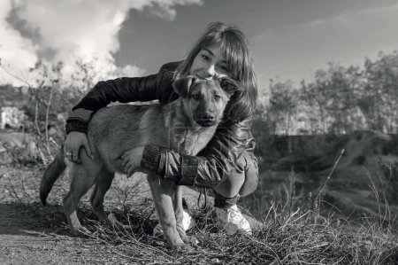 Téléchargez les photos : Chien dans un abri. Un bénévole d'un refuge pour animaux s'occupe des chiens. Un bénévole s'occupe d'un chien dans un refuge. Image en blanc noir - en image libre de droit