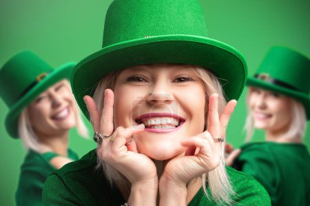 Día de San Patricio. Tres mujeres alegres con sombreros de duende celebran el Día de San Patricio. Humor festivo sobre un fondo verde brillante
