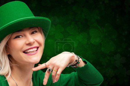 Smiling woman in green attire with leprechaun hat against a clover backdrop