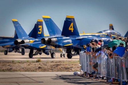 Photo for Fans of the US Navy Blue Angels line up at the fence as the team taxis for take-off at the 2022 Miramar Airshow in San Diego, California. - Royalty Free Image