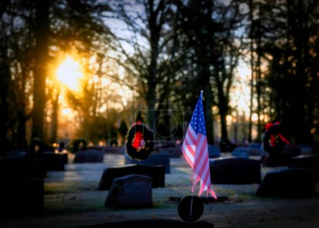Foto de El sol se levanta en banderas americanas y coronas de Navidad en un cementerio de Wisconsin. - Imagen libre de derechos