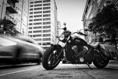 Photo for Traffic passes an Indian Scout motorcycle parked on the street in Chicago, Illinois. - Royalty Free Image